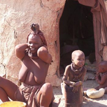 Prachtige jonge himba vrouw voor haar hut